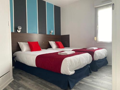 two beds in a hotel room with red and white pillows at Fasthotel Tours Nord in Parçay-Meslay