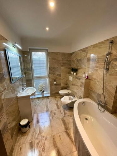 a bathroom with a tub and a toilet and a sink at Penzion Vegas in Partizánske