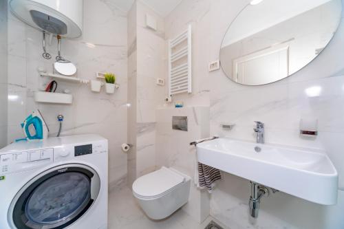 a white bathroom with a washing machine and a sink at Les appartements Privés Bar in Bar