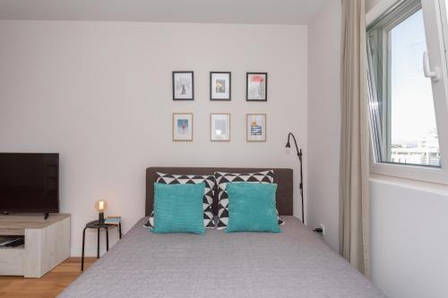 a bedroom with a bed with blue pillows and a television at Les appartements Privés Bar in Bar
