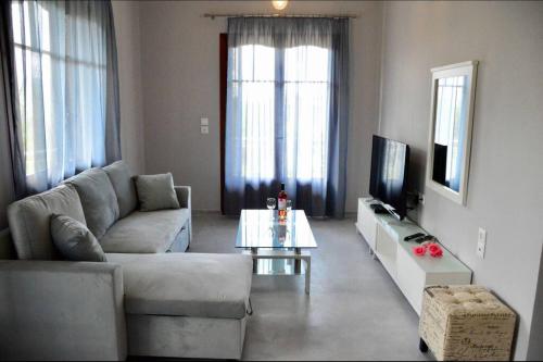 a living room with a couch and a tv at Sea Breeze Apartments - n.1 with private pool in Kalamitsi