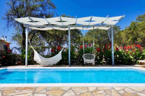 a white umbrella and a hammock next to a pool at Sea Breeze Apartments - n.1 with private pool in Kalamitsi