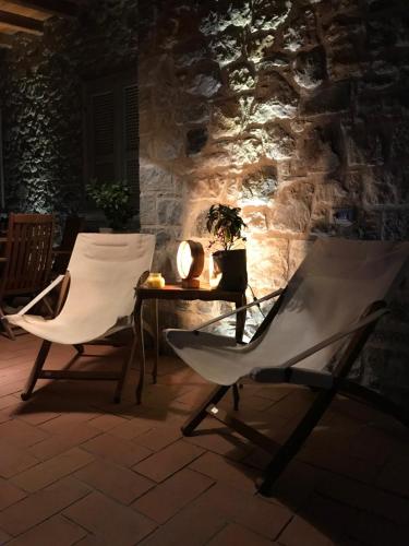 a table and chairs in front of a stone wall at LE LANTERNE in Villa dʼAlmè