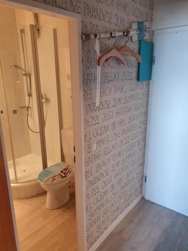 a bathroom with a shower and a toilet with writing on the wall at Kleine Hafenliebe in Fehmarn