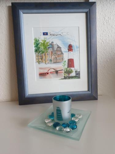 a picture of a lighthouse and a cup on a shelf at Kleine Hafenliebe in Fehmarn