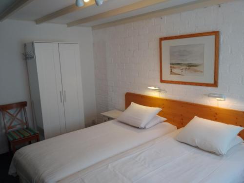 2 weiße Betten in einem Schlafzimmer mit einem Bild an der Wand in der Unterkunft De Kersentuin in Nieuwvliet