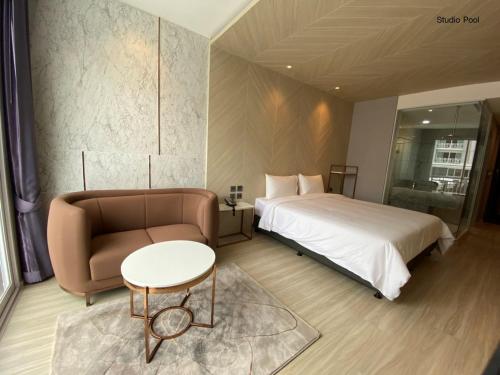 a bedroom with a bed and a couch and a table at Golden City Rayong Hotel in Rayong
