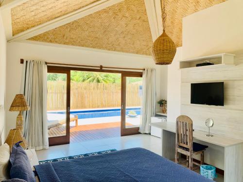 a bedroom with a bed and a desk and a television at Villa Ferradura Mar in Búzios
