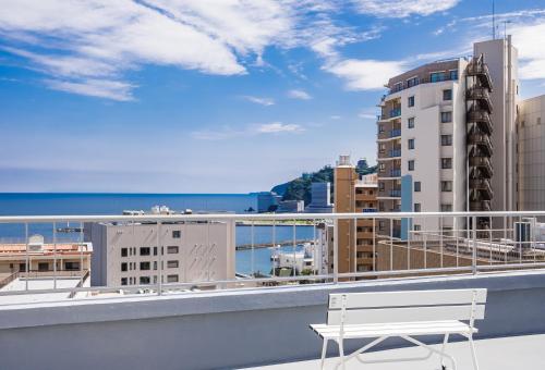 a white bench on a balcony with a view of the ocean at 素泊まり宿　瑞宝荘 in Atami