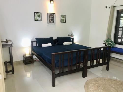 a bedroom with a large bed with blue sheets at Tamarind Villa in Varkala