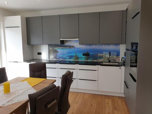 a kitchen with white cabinets and a wooden table at Golf & Ski Appartements Mittersill Trausmuth Monika inkl Sommercard - Golfplatz 500 m entfernt, inkl Waschmaschine, Trockner in Mittersill