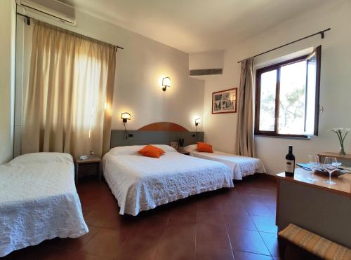 a hotel room with two beds and a window at Locanda Menabuoi in Donoratico