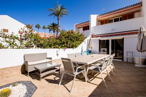 un patio con mesa y sillas y un edificio en GO2TENERIFE Tropicana Villa Santiago 2, en Playa de las Américas