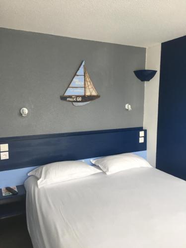 1 dormitorio con 1 cama con una vela en la pared en Initial by balladins Dieppe, en Saint-Aubin-sur-Scie