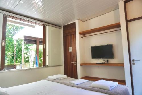 1 dormitorio con 1 cama, TV y ventana en Chalés Maritacas, en Maresias