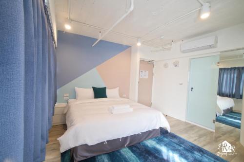 a bedroom with a white bed and a blue wall at Jezreel Inn in Kaohsiung