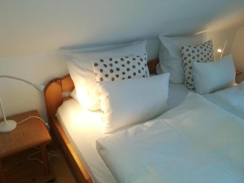 a bed with white sheets and pillows in a room at Ferienhof Trapp in Ellringen