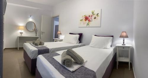 two beds in a room with two tables and a mirror at Levanda Guest Houses in Andiparos
