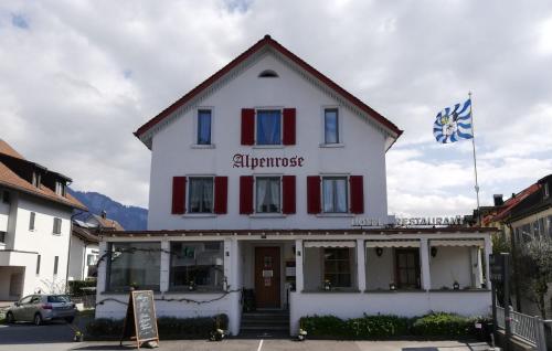a white building with a flag on top of it at Hotel Alpenrose in Maienfeld