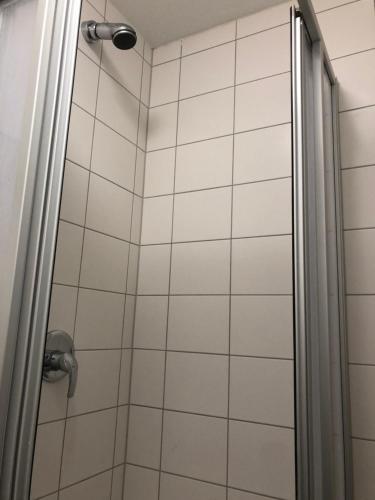 - une douche avec un mur carrelé blanc dans l'établissement Panorama Hostel, à Francfort-sur-le-Main