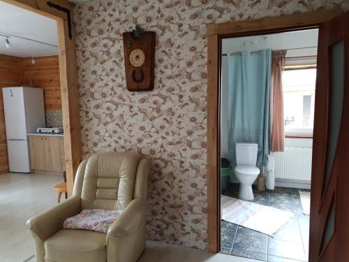 a living room with a chair and a clock on the wall at Kāpas in Jūrkalne