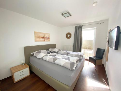 Schlafzimmer mit einem Bett, einem TV und einem Stuhl in der Unterkunft Ferienwohnungen Residenz Hohe Lith - Duhnen in Cuxhaven