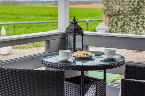a table with two cups and a plate of food on a porch at Sunset log cabin in Sudbury