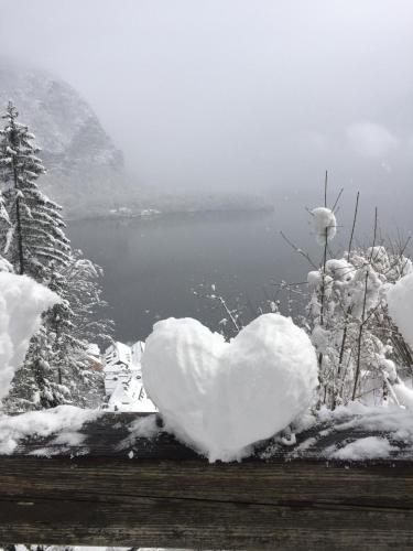 a heart covered in snow in front of a lake at Appartement Emilia in Hallstatt