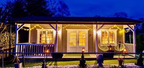 a small house with lights on the front of it at The Retreat Log Cabin in Sudbury