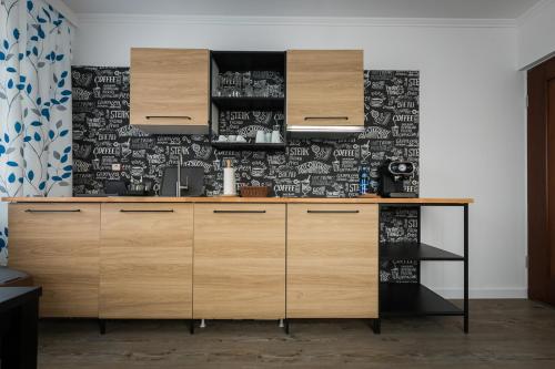 a kitchen with wooden cabinets and a black and white wallpaper at ApartsW241 in Jelenia Góra