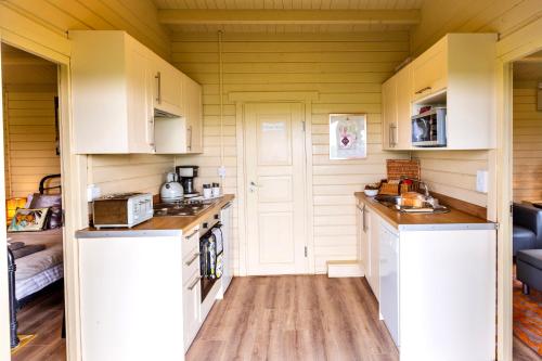 a small kitchen with white cabinets and wooden floors at The Retreat Log Cabin in Sudbury