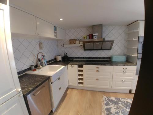 a kitchen with white cabinets and a sink at Rosdala gård - gästhuset in Rydsgård