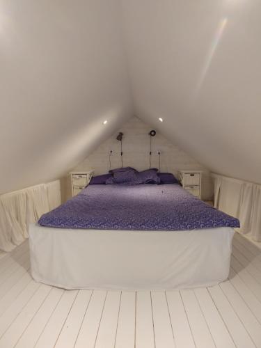 a bedroom with a large bed with purple sheets at Rosdala gård - gästhuset in Rydsgård