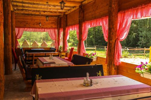 una sala da pranzo con tavoli, sedie e finestre di Camp Sutjeska a Tjentište