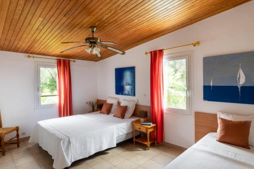 two beds in a room with red curtains at Residence Helios in Cargèse