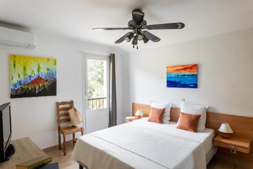a bedroom with a bed and a ceiling fan at Residence Helios in Cargèse