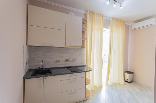 a kitchen with white cabinets and a sink and a window at Villa Grey House in Berehove