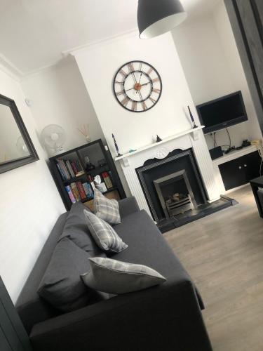 a living room with a couch and a clock on the wall at City Centre Victorian Terrace in Cardiff