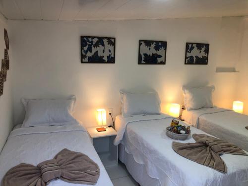 Dos camas en una habitación con dos lámparas y toallas. en Toca da Villa en Fernando de Noronha