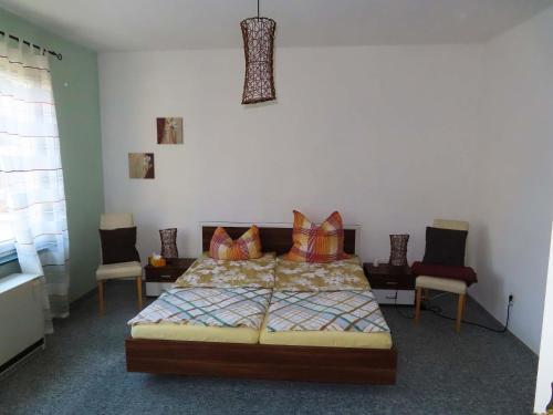 ein Schlafzimmer mit einem Bett und Stühlen in der Unterkunft Ferienwohnungen am Weinberg Bad Sulza in Bad Sulza