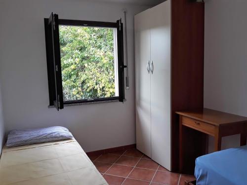 Dormitorio con ventana, cama y mesa en Il sughereto, en Àrbatax