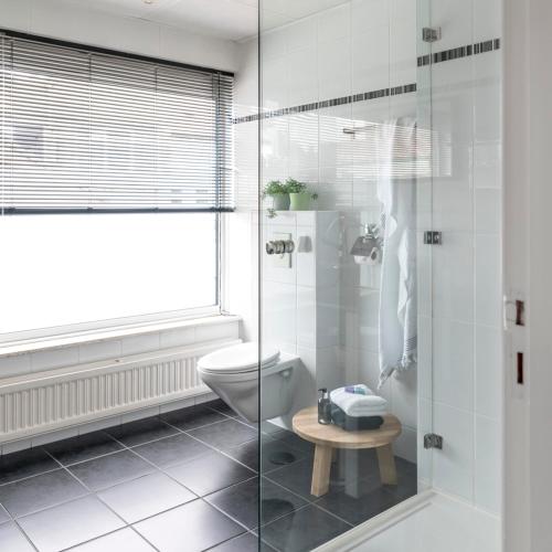 a bathroom with a toilet and a glass shower at B&B De Kluis Axel in Axel