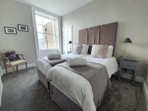a bedroom with two beds and a chair and a window at Park View Two-Bedroom Apartment in Bath