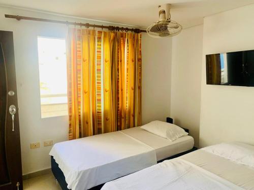 1 dormitorio con 2 camas y una ventana con cortinas en Santa Marta Apartamentos - Brisas Marina, en Santa Marta