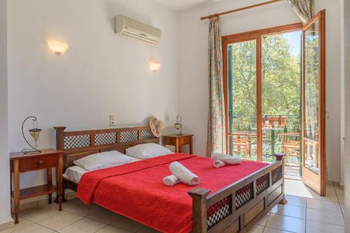 a bedroom with a large bed with a red blanket at Des Roses Hotel in Platanias