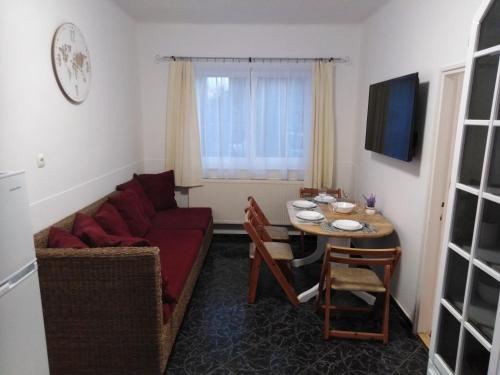 ein Wohnzimmer mit einem roten Sofa und einem Tisch in der Unterkunft Arinza Apartman Vendégház in Mezőkövesd