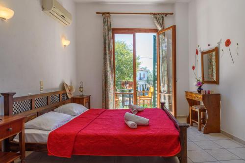a bedroom with a red bed with a teddy bear on it at Des Roses Hotel in Platanias