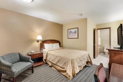 a hotel room with a bed and a chair at Rodeway Inn Columbus West in Columbus