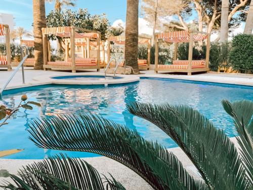 a swimming pool with chairs and palm trees at Villa Piccola by Cassai in Colònia de Sant Jordi