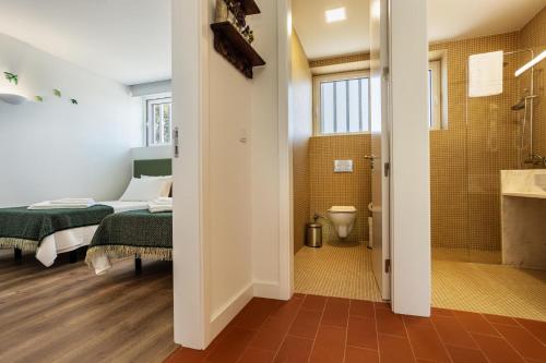 a bedroom with a bed and a bathroom with a shower at QSF Agro Turismo Quinta da Sagrada Família in Évora